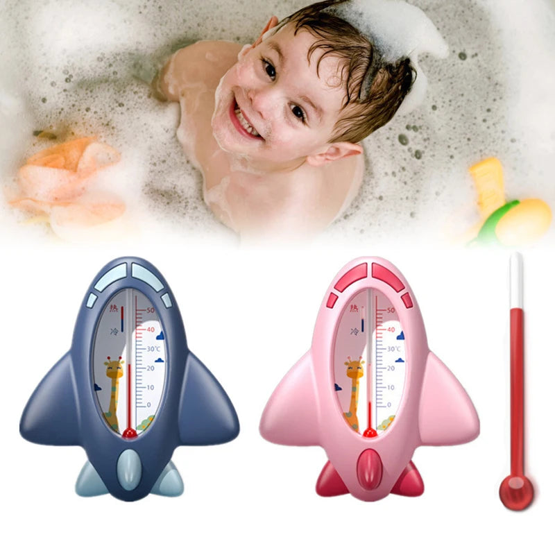 Child-friendly rocket-shaped bath thermometers in blue and pink with animal designs and temperature display, alongside a traditional thermometer, with a joyful child in a bubble bath in the background.