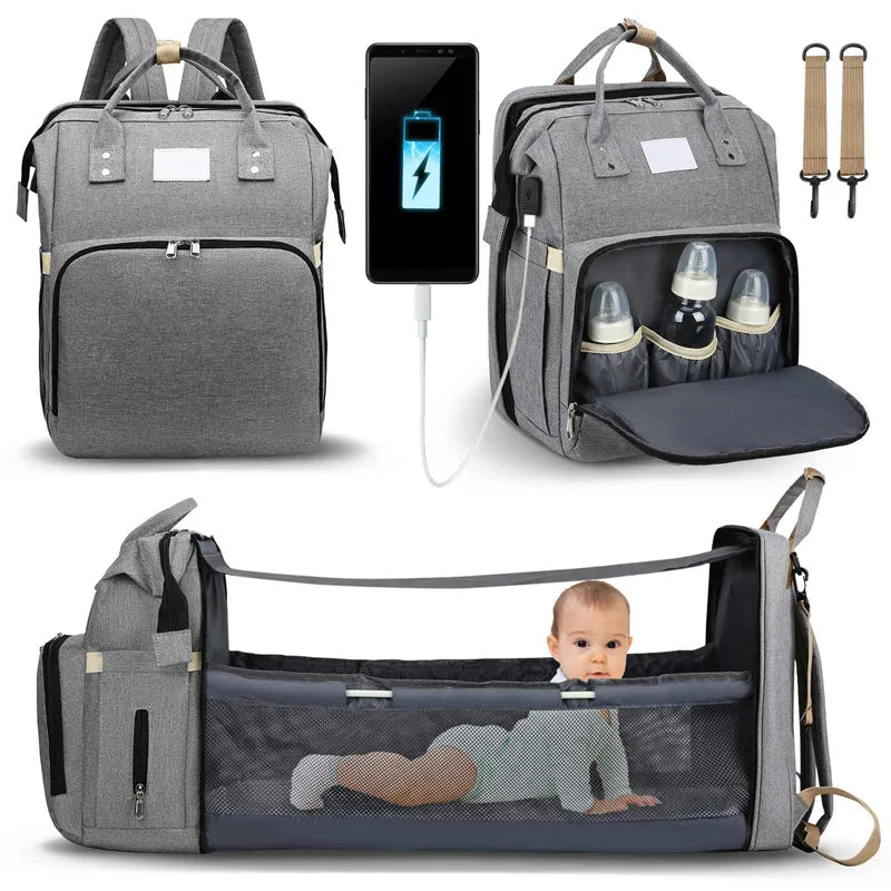 Multi-functional grey baby diaper backpack with insulated bottle storage, expandable portable crib feature, and USB charging port, demonstrated with baby bottles and a charging smartphone, ideal for traveling parents.