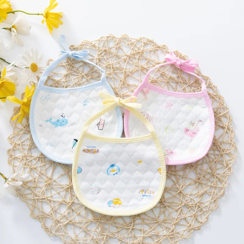 Set of three quilted baby bibs with whimsical patterns and pastel borders in blue, yellow, and pink, displayed on a woven mat with daisy decorations, perfect for infants.