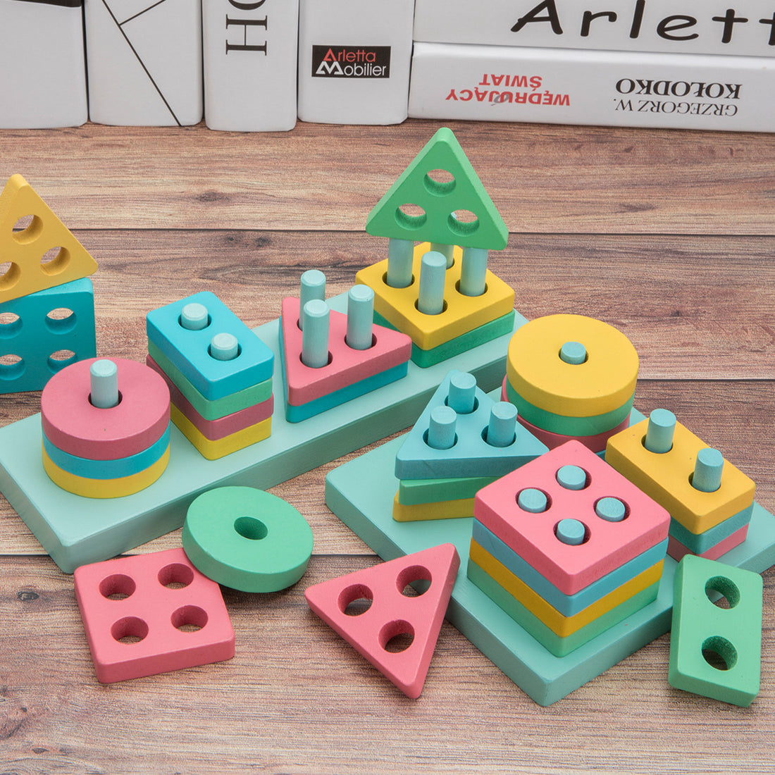 Assortment of pastel-colored geometric shape sorter and stacking toys for children, set on a wooden table, designed to enhance cognitive and motor skills through play.